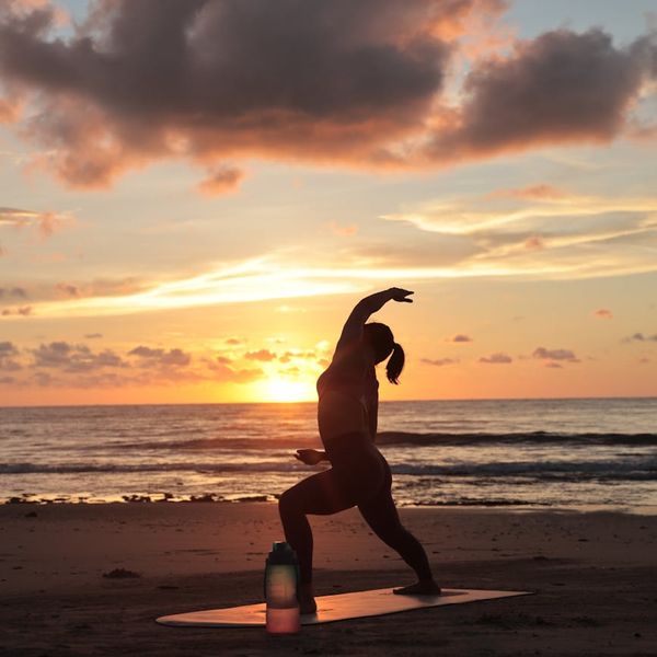 Silhouette of a person stretching during sunrise with warm tones.